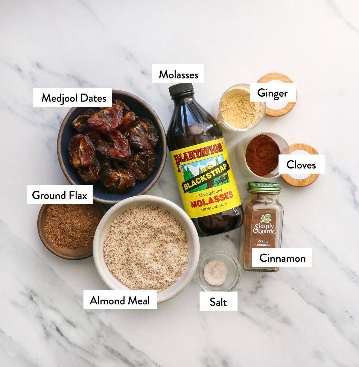 medjool dates, molasses, almond meal, ground flax, and spices labeled on a white surface. 