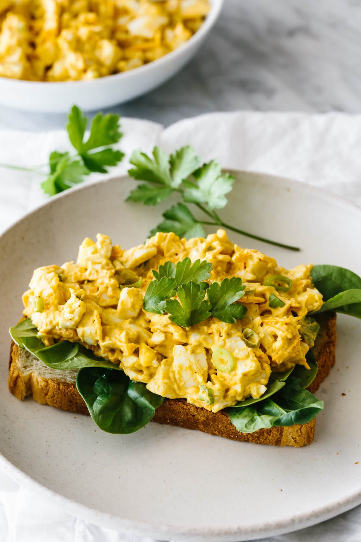 Curried egg salad on top of spinach and bread makes an open faced sandwich.
