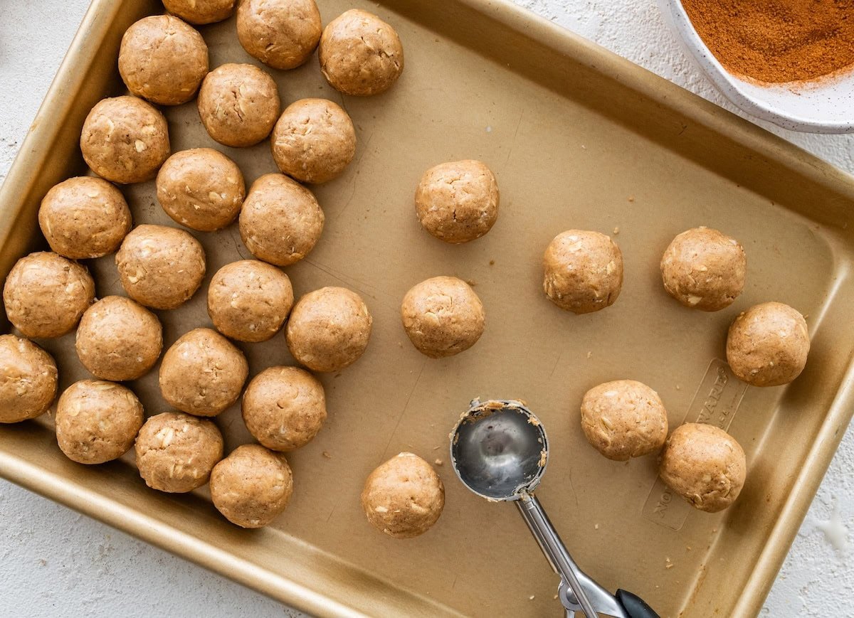 Uncoated protein balls Uncoated protein balls arranged on a baking sheet beside a small cookie scoop.