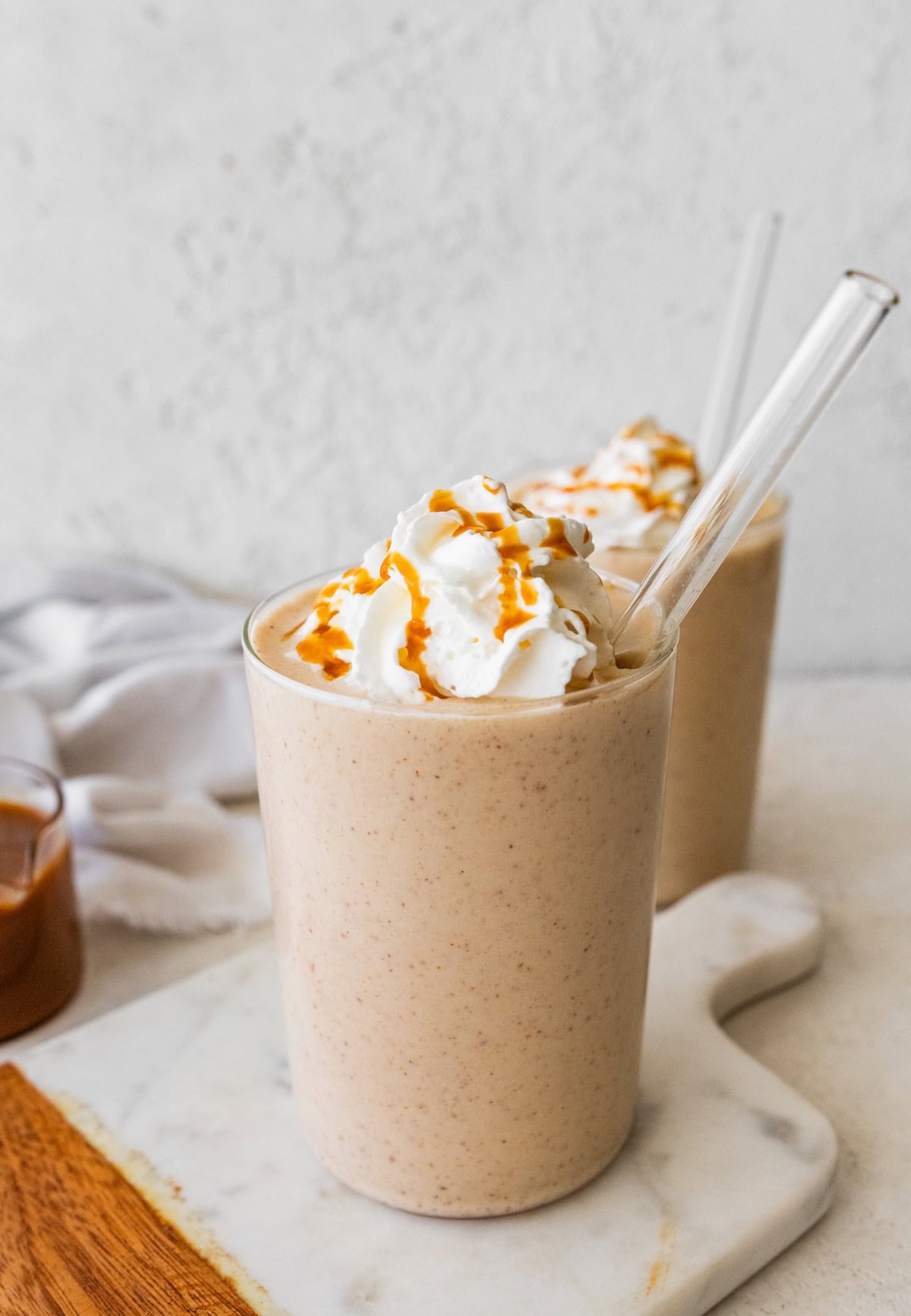 Creamy salted caramel protein shake in a glass with whipped cream and caramel drizzle.