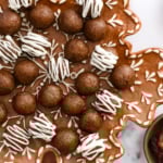 gingerbread energy balls topped with white chocolate on a snowflake plate.