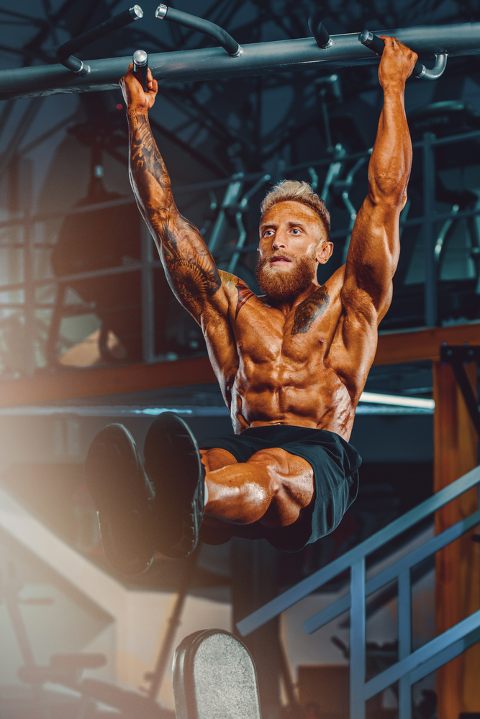 Ripped man doing hanging leg raises at the gym