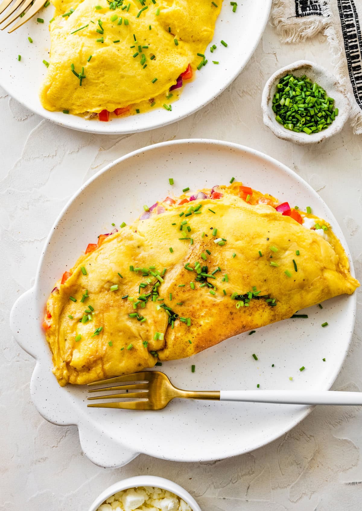 Golden cottage cheese omelette on a plate with chives, ready to slice and serve.