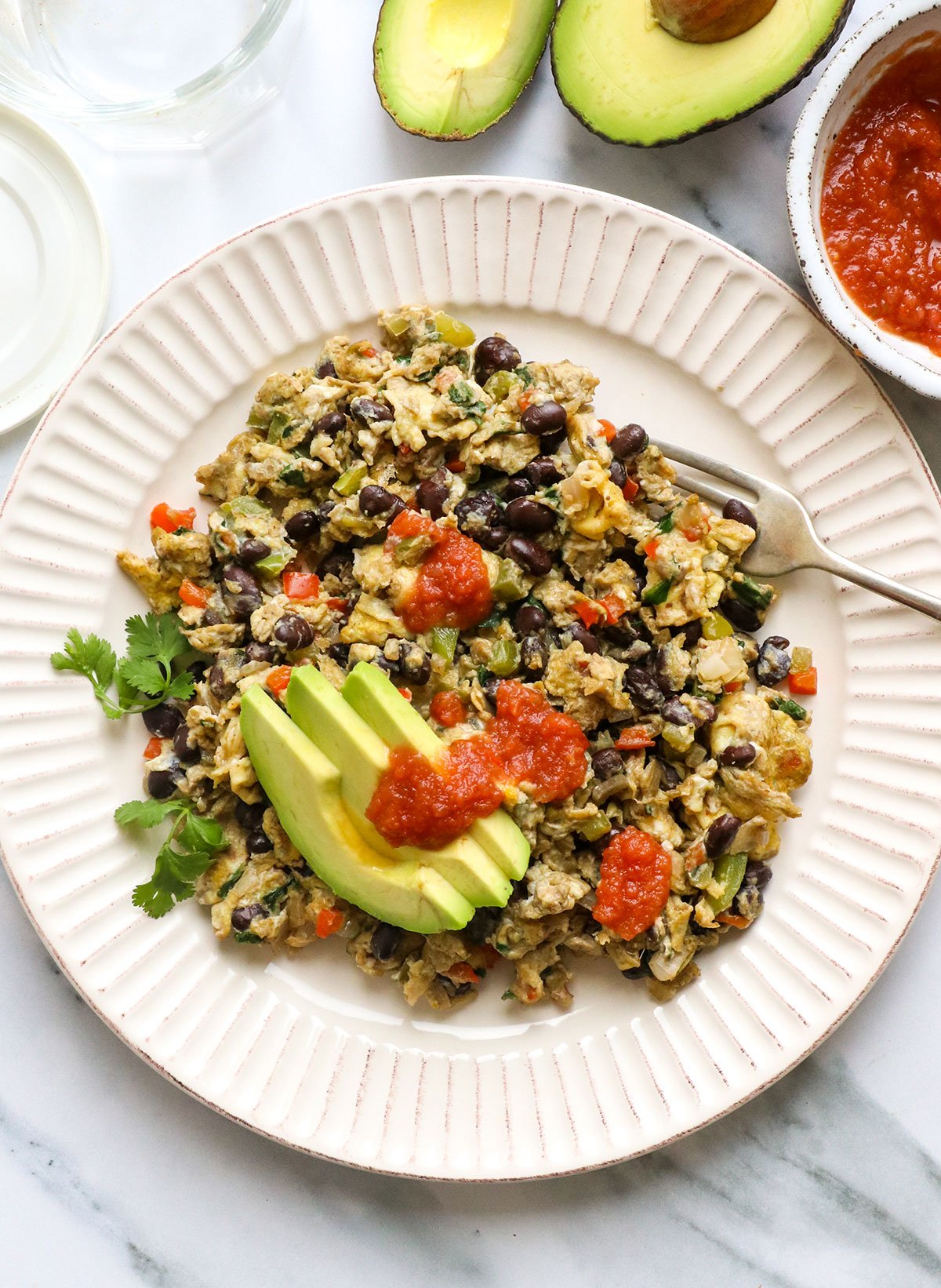 high protein breakfast scramble topped with avocado slices and salsa.