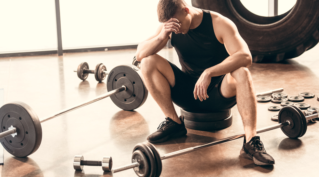 Tired-Man-Surrounded-By-Weights