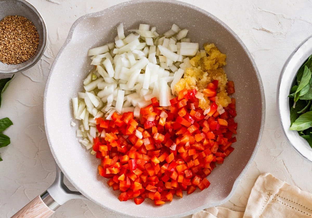Diced onion, bell pepper and minced garlic added to a skillet before sautéing.