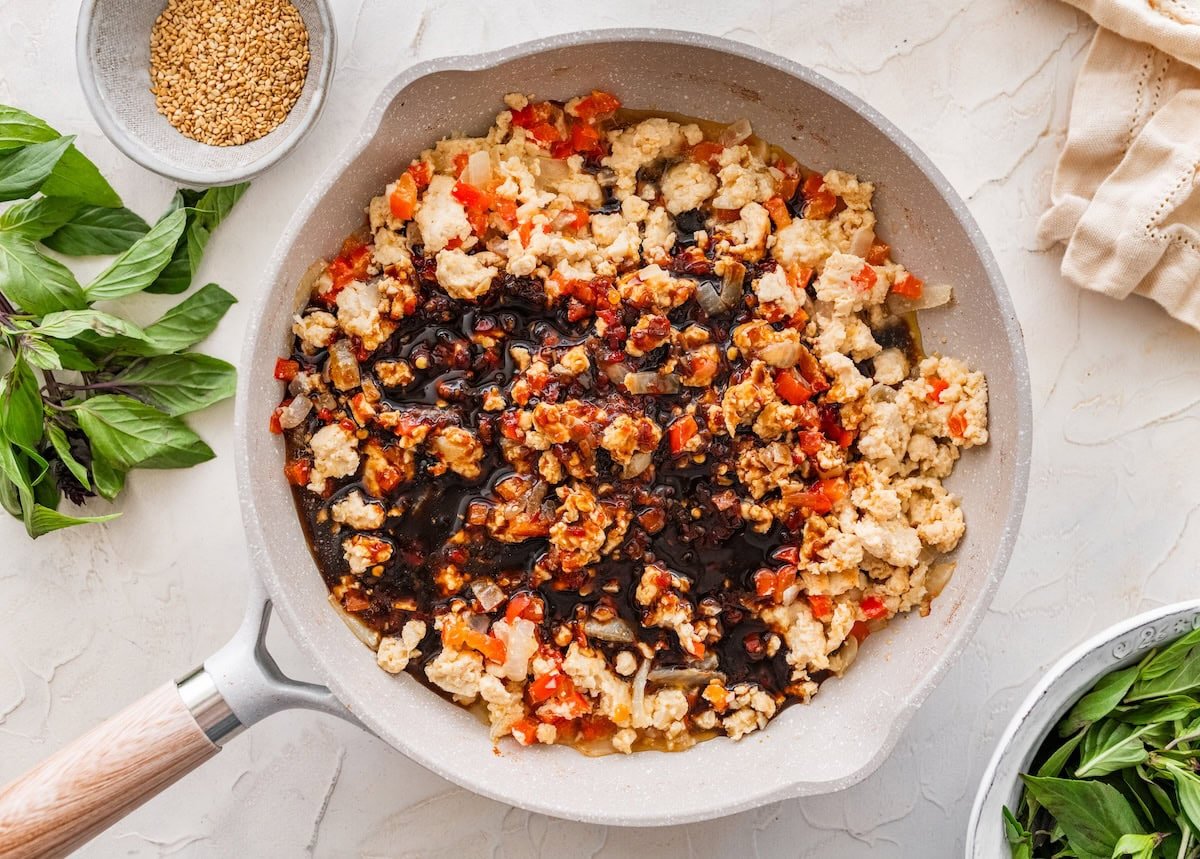 Ground chicken stir fry in a skillet with dark savory sauce poured over the mixture.