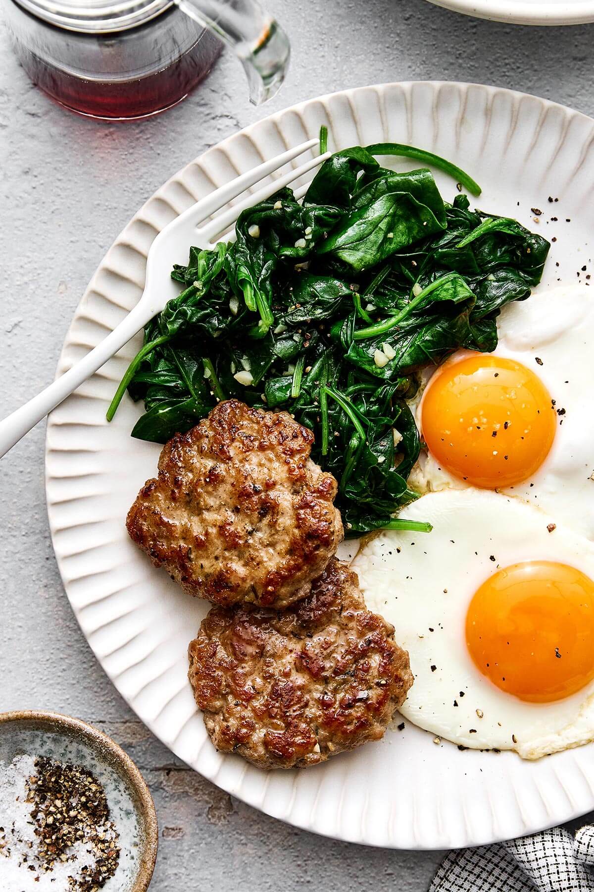 Breakfast plate with eggs, chicken sausage, and spinach.