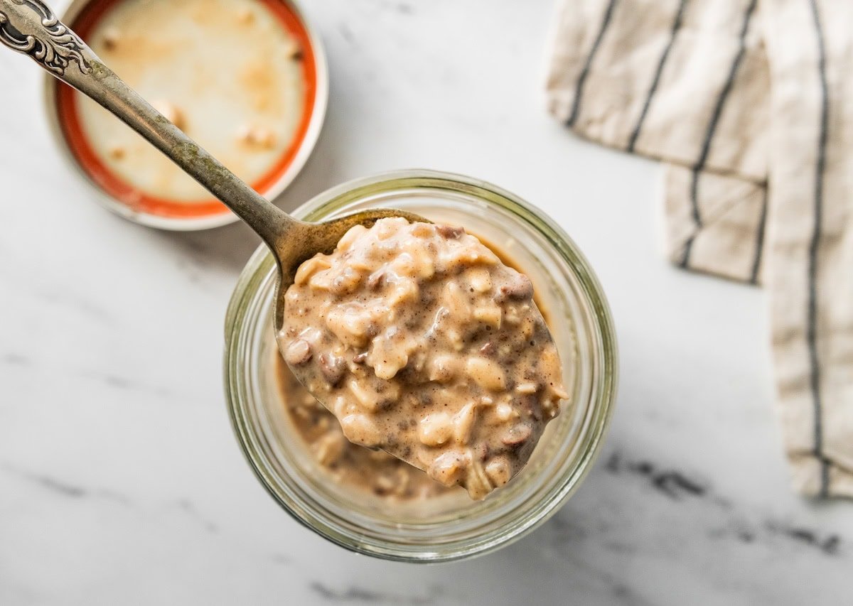 Creamy cookie dough overnight oats in a glass jar with chocolate chips and cinnamon.