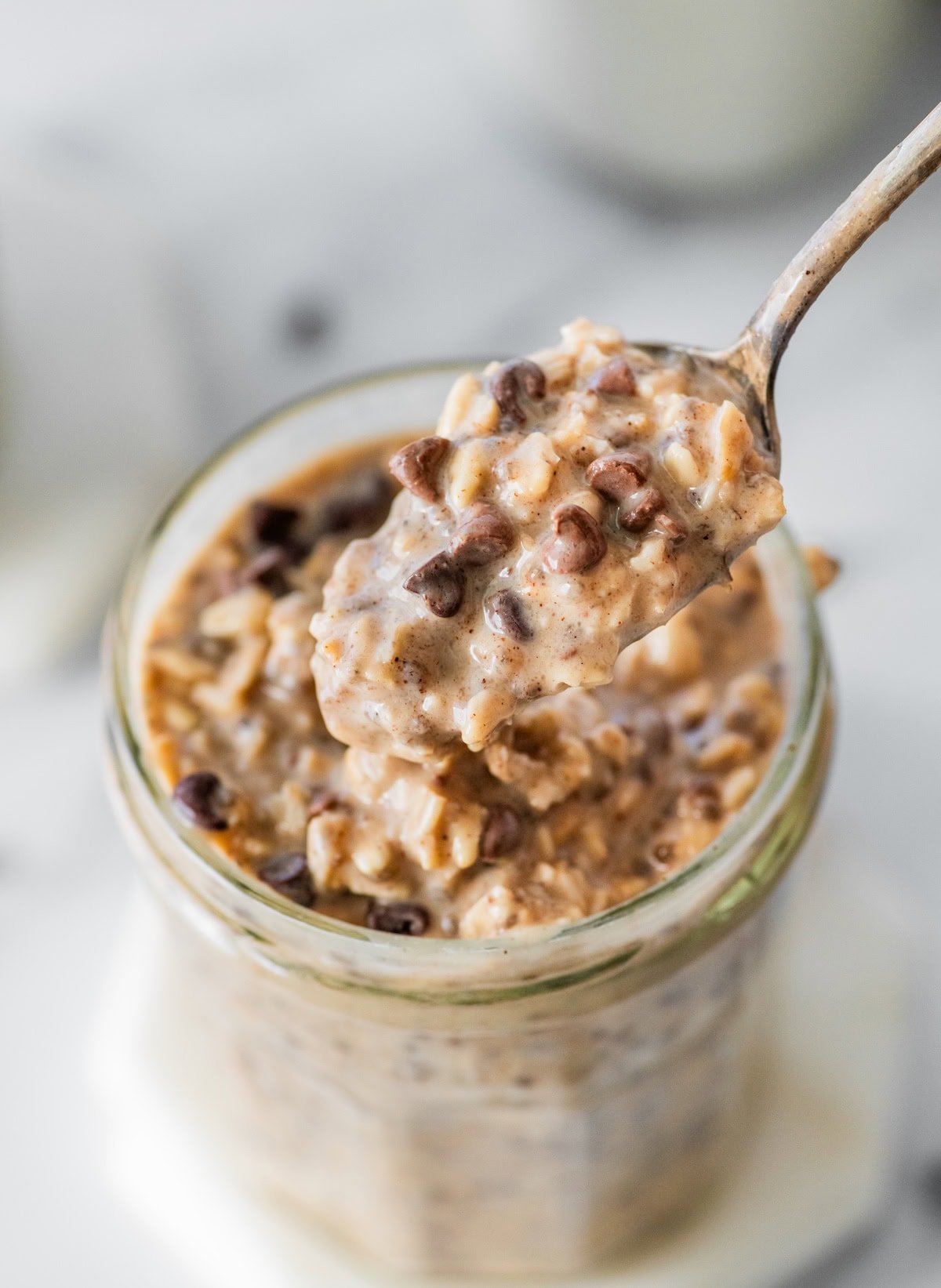 Spoonful of creamy cookie dough overnight oats with chocolate chips lifted from a jar.