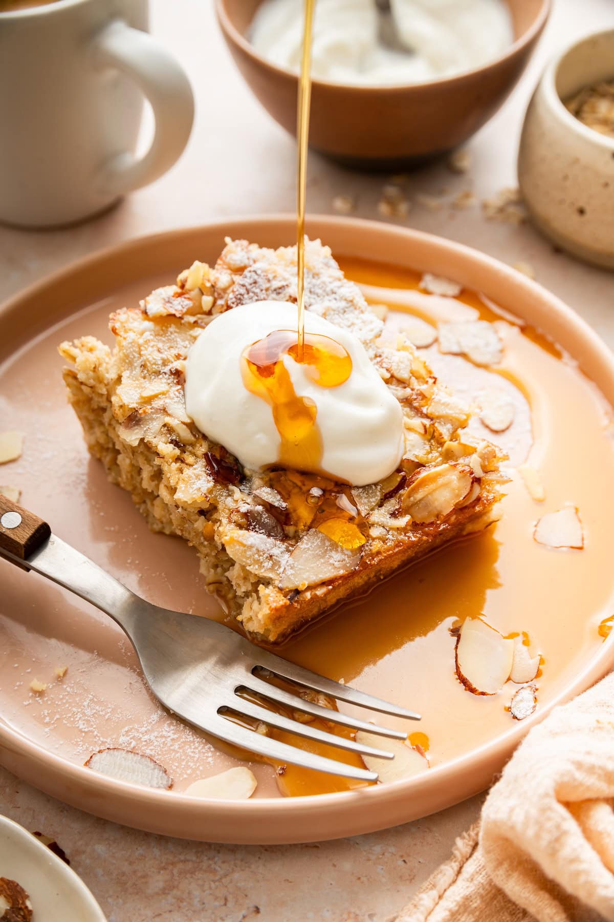Slice of almond croissant baked oatmeal topped with yogurt and maple syrup.