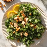 kale caesar salad topped with chicken and tahini dressing.