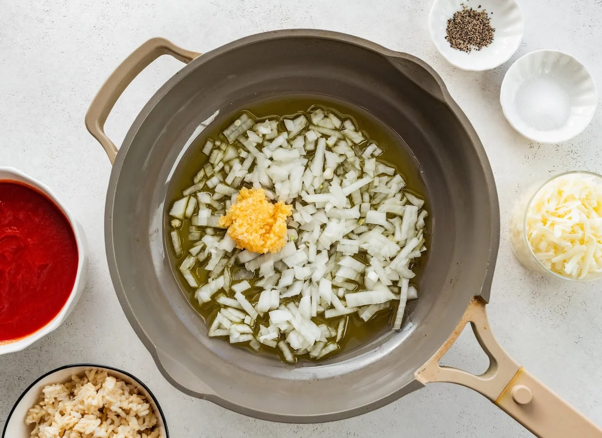 Diced onion and garlic being sauteed in a pan.