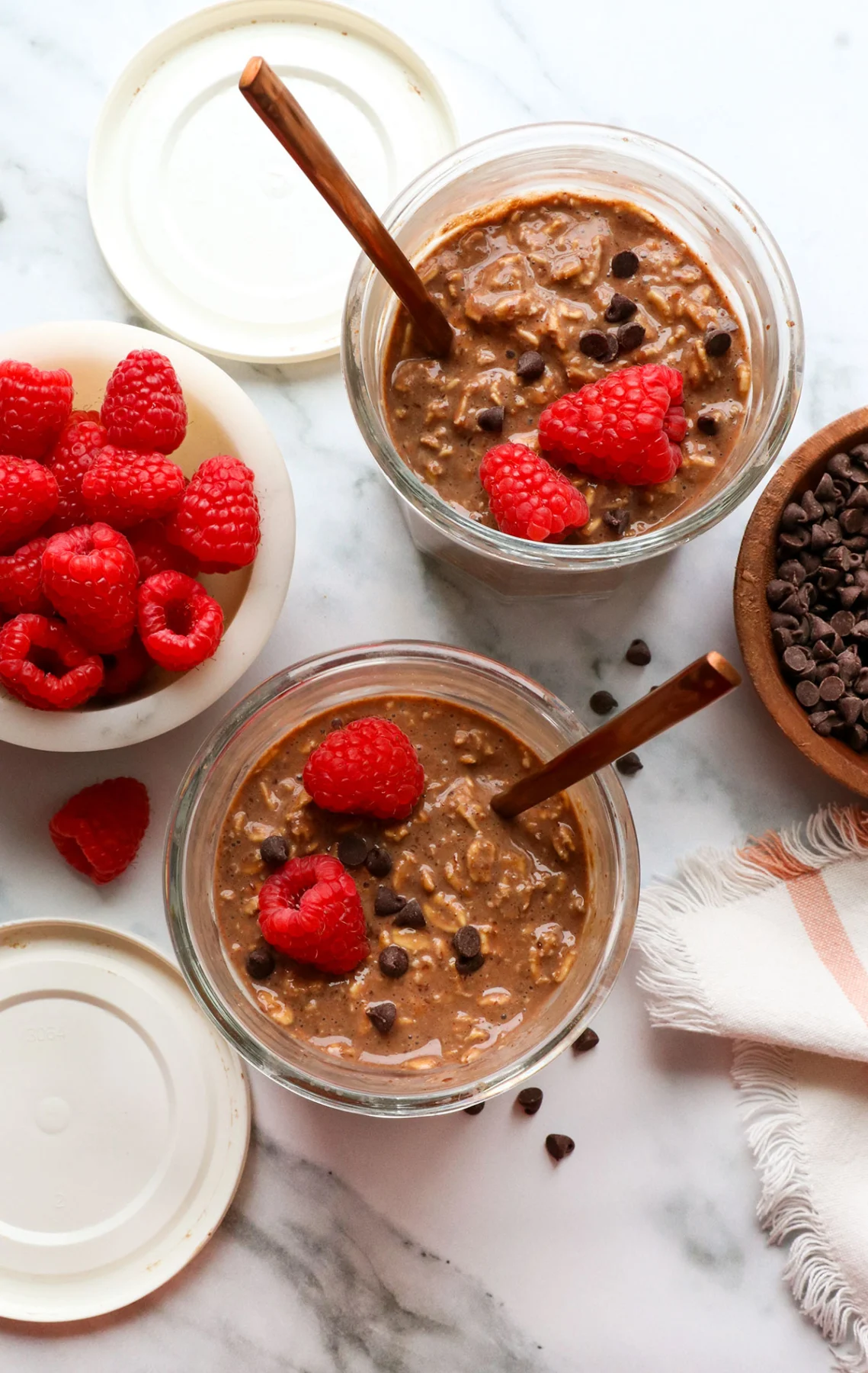 two jars of chocolate overnight oats topped with raspberries.