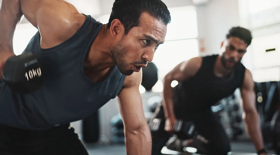 Fit older male breathing and grunting during a difficult workout using dumbbell rows