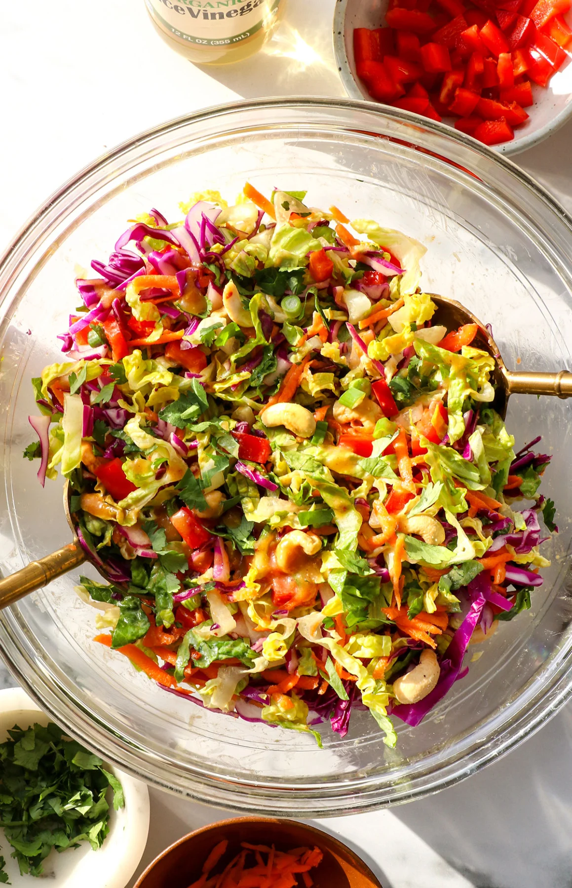 thai salad tossed in a glass bowl with cashews on top. 
