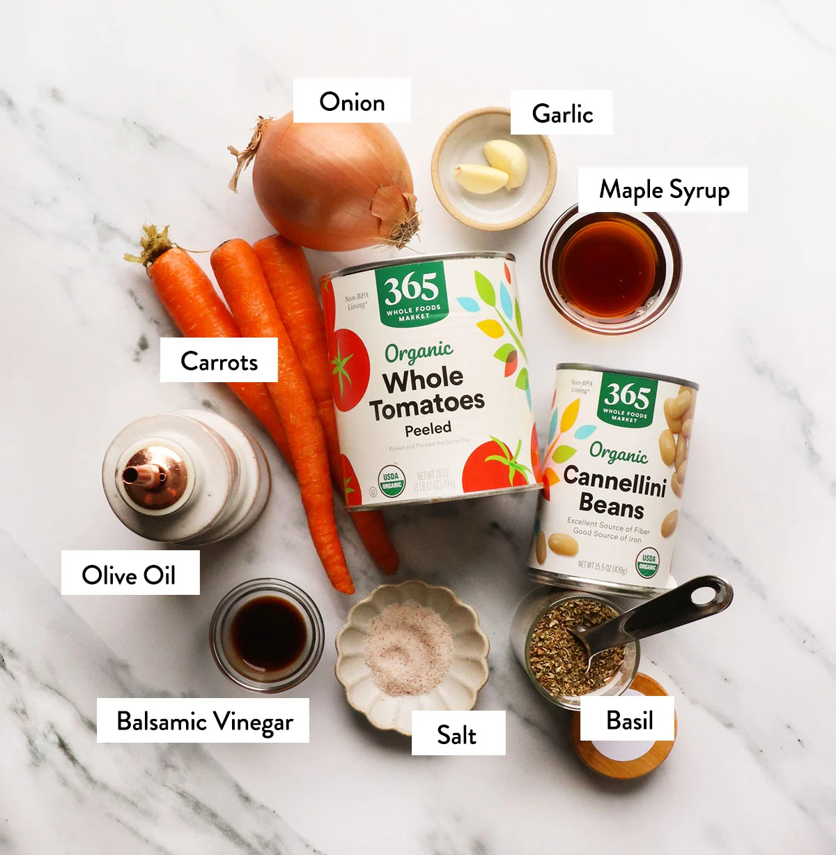 canned tomatoes, carrots, onion, garlic, beans, and spices labeled on a white surface. 