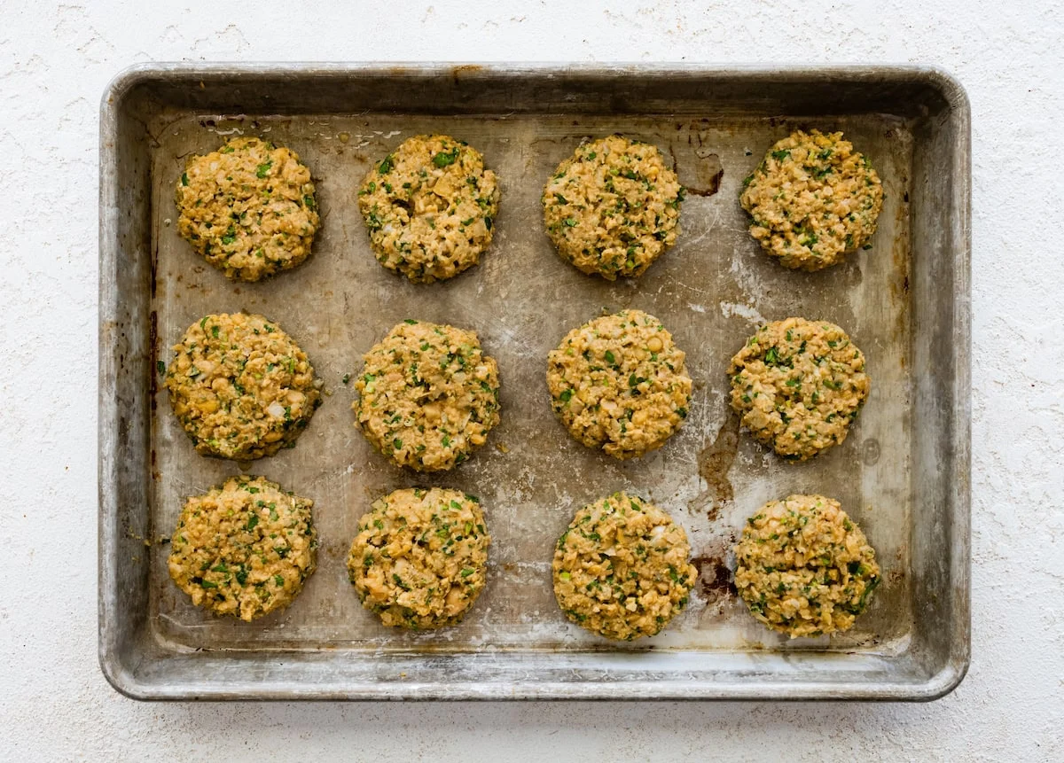 Raw falafel mixture portioned into scoops on baking sheet before baking.