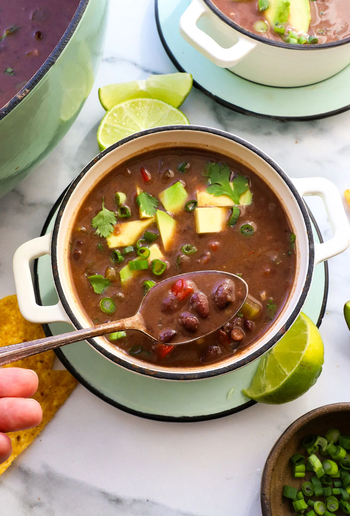 black bean soup lifted on a spoon over a white bowl.
