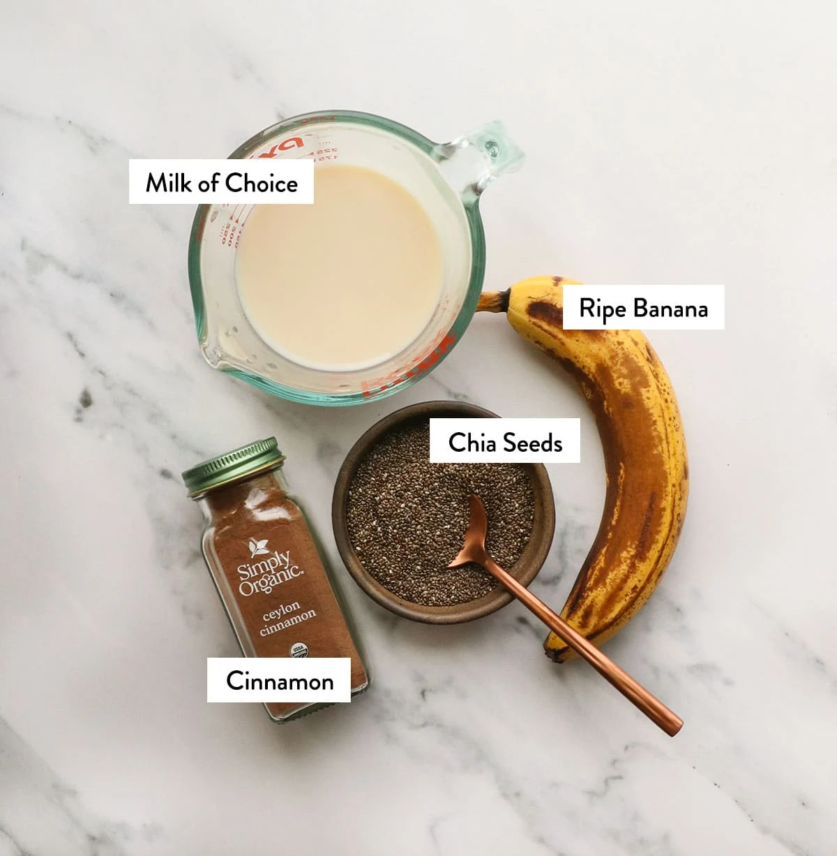banana, chia seeds, milk, and cinnamon labeled on a white surface.