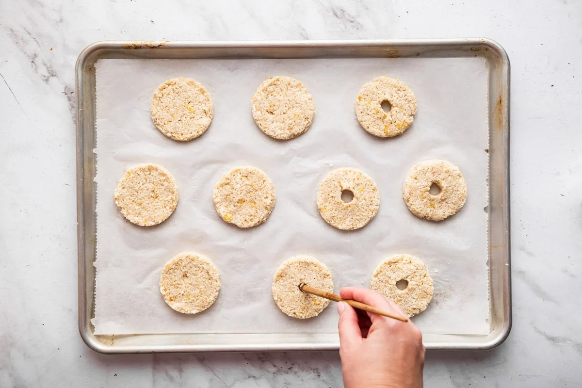 A womans hand uses a wooden chop stick to poke holes in banana samoas cookie dough to form the classic samoas cookie shape.