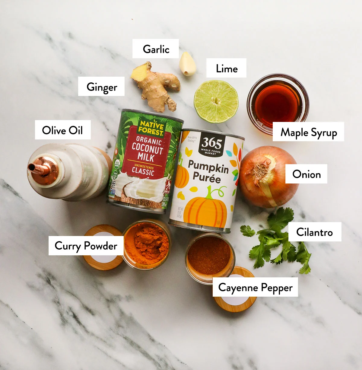 pumpkin, coconut milk, curry powder, lime, garlic, and ginger labeled on a white surface. 