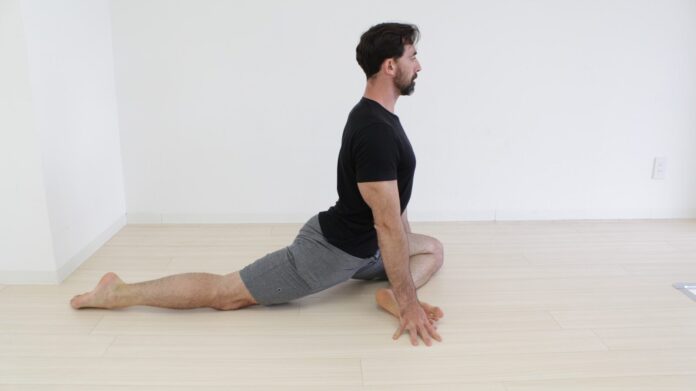 a man sitting on the floor doing a yoga pose